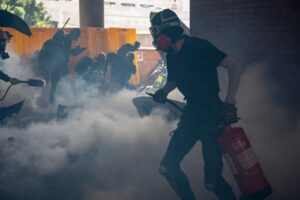 University students and protesters react after police fire tear gas to the campus of the Hong Kong Polytechnic University during a protest on November 11, 2019. – A Hong Kong police officer shot at masked protesters — hitting at least one in the torso — during clashes broadcast live on Facebook, as the city’s rush hour was interrupted by protests. (Photo by Philip FONG / AFP)