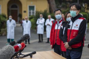 Sun Shuopeng, Vice President of China’s Red Cross, right, flanked by respiratory diseases expert from the Sichuan University, Zongan Liang, third from right, speaks to journalists outside the Spallanzani Hospital for Infectious Diseases in Rome, Saturday, March 14, 2020. For most people, the new coronavirus causes only mild or moderate symptoms. For some, it can cause more severe illness, especially in older adults and people with existing health problems. In the background doctors from the Spallanzani Hospital. (AP Photo/Domenico Stinellis)