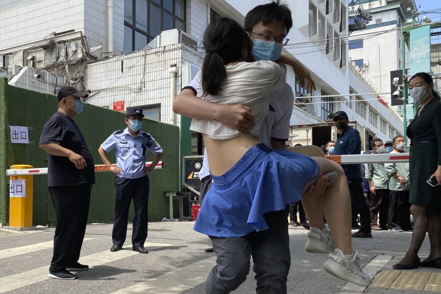 A woman is carried out from a coronavirus testing center set up outside a sports facility in Beijing, Tuesday, June 16, 2020. China reported several dozen more coronavirus infections Tuesday as it increased testing and lockdown measures in parts of the capital to control what appeared to be its largest outbreak in more than two months. (AP Photo/Ng Han Guan)