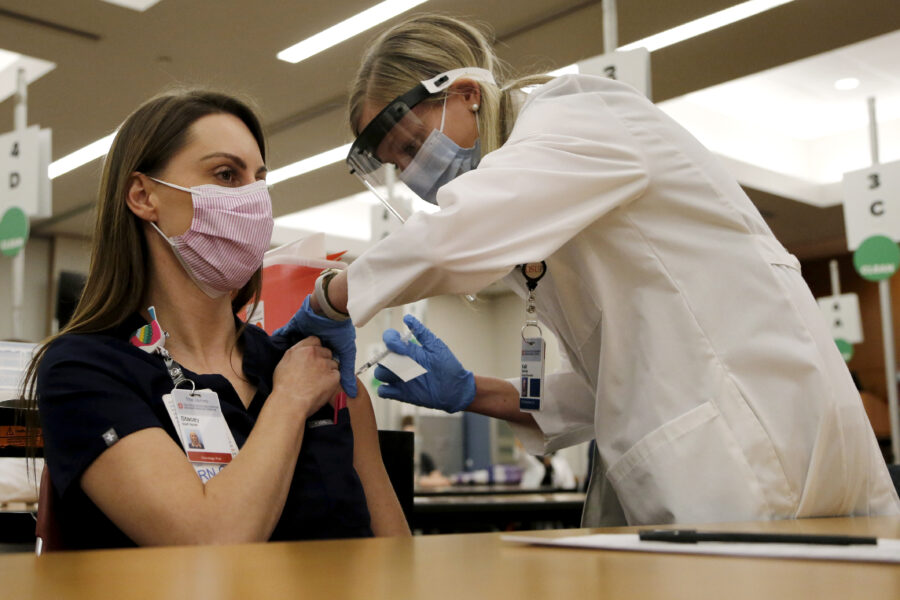 Ohio State employee Stacey Boyer, left, receives a Pfizer-BioNTech COVID-19 vaccine from Kelli Barnes Monday, Dec. 14, 2020, in Columbus, Ohio. (AP Photo/Jay LaPrete)