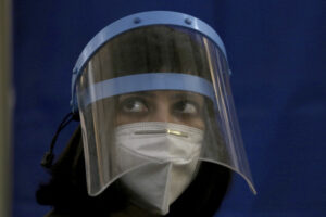 A doctor wears a face mask and shield to protect against the coronavirus while she wait for to receive a Sinopharm coronavirus vaccine at a vaccination center, in Karachi, Pakistan, Wednesday, Feb. 3, 2021. Pakistani authorities started vaccinating frontline health workers on Wednesday amid a steady decline in confirmed cases and fatalities, and days after Pakistan received half a million doses of the Sinopharm vaccine donated by China. (AP Photo/Fareed Khan)