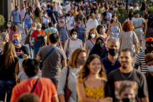 People wearing a face mask to protect against the spread of coronavirus walk along a street in downtown Barcelona, Spain, Saturday, July 3, 2021. The need to speed up vaccine rollouts has become more urgent as the COVID-19 delta variant spreads quickly. (AP Photo/Joan Mateu)