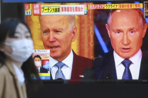 A woman walks past a TV screen showing images of Russia’s President Vladimir Putin and U.S. President Joe Biden in Tokyo, Thursday, Feb. 24, 2022. Russian troops launched a wide-ranging attack on Ukraine on Thursday, as President Vladimir Putin cast aside international condemnation and sanctions and warned other countries that any attempt to interfere would lead to “consequences you have never seen.” (AP Photo/Koji Sasahara)