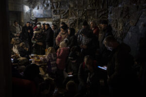 People gather in a basement, used as a bomb shelter, during an air raid in Lviv, Western Ukraine, Saturday, March 19, 2022. Lviv has been a refuge since the war began nearly a month ago, the last outpost before Poland and host to hundreds of thousands of Ukrainians streaming through or staying on. (AP Photo/Bernat Armangue)