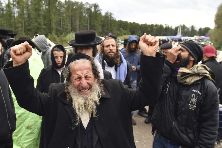 A Hasidic Jewish pilgrim reacts as he joins others, in front of Ukrainian border guards at the checkpoint Novaya Guta near Novaya Guta, Belarus, Friday, Sept. 18, 2020. Ukrainian officials say that thousands of Hasidic Jewish pilgrims stuck on the Ukrainian border due to coronavirus restrictions have started turning back. About 2,000 ultra-Orthodox Jewish pilgrims traveled to Belarus’s border with Ukraine in hope of traveling to the Ukrainian city of Uman to visit the grave of an important Hasidic rabbi who died in 1810, Nachman of Breslov. (AP Photo)