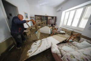 A walks among mud and debris in his home after heavy rainfall triggered landslides that collapsed buildings and left as many as 12 people missing, in Casamicciola, on the southern Italian island of Ischia, Sunday, Nov. 27, 2022. Authorities said that the landslide that early Saturday destroyed buildings and swept parked cars into the sea left one person dead and 12 missing. (AP Photo/Salvatore Laporta)