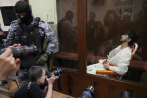Muhammadsobir Fayzov, a suspect in the Crocus City Hall shooting on Friday sits in a glass cage in the Basmanny District Court in Moscow, Russia, Sunday, March 24, 2024. (AP Photo/Alexander Zemlianichenko)