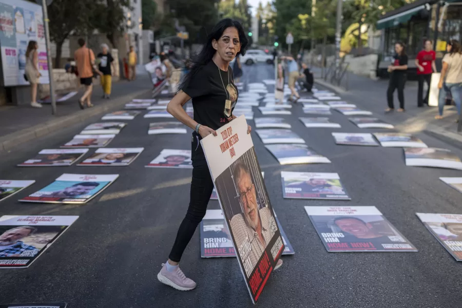 Einav Zangauker, the mother of Matan Zangauker who is being held by Hamas in Gaza, picks up a photo of Yoram Metzger whose body was recovered by Israel’s military during an operation in the Gaza Strip, during a protest outside Prime Minister Benjamin Netanyahu’s residence in Jerusalem, Friday, Aug. 30, 2024. (AP Photo/Ohad Zwigenberg)