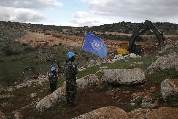 FILE – UN peacekeepers hold their flag, as they observe Israeli excavators attempt to destroy tunnels built by Hezbollah, near the southern Lebanese-Israeli border village of Mays al-Jabal, Lebanon on Dec. 13, 2019. Four United Nations military observers were wounded Saturday while patrolling along the southern Lebanese border after a shell exploded near them, the U.N. peacekeeping mission in southern Lebanon said. The military observers of the United Nations Truce Supervision Organization support the U.N. peacekeeping mission in southern Lebanon, UNIFIL.  (AP Photo/Hussein Malla, File)