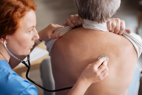 Take a deep breath. Skillful trained private doctor using professional stethoscope for hearing how elderly man breathing and diagnosing him